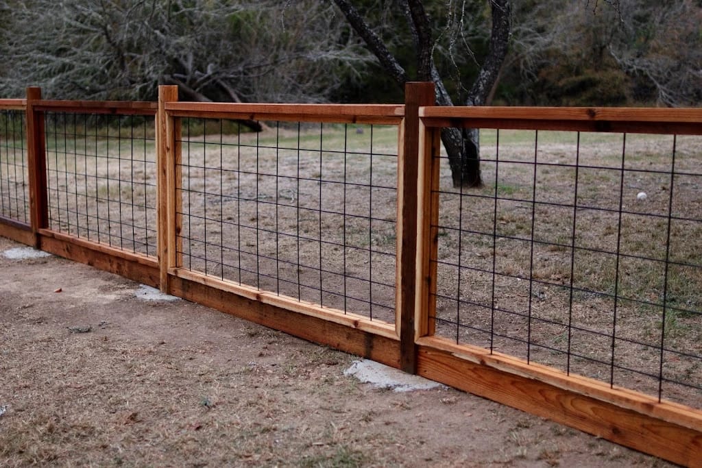 A finished cedar-frame fence with black welded-wire panels, built in Bastrop County.